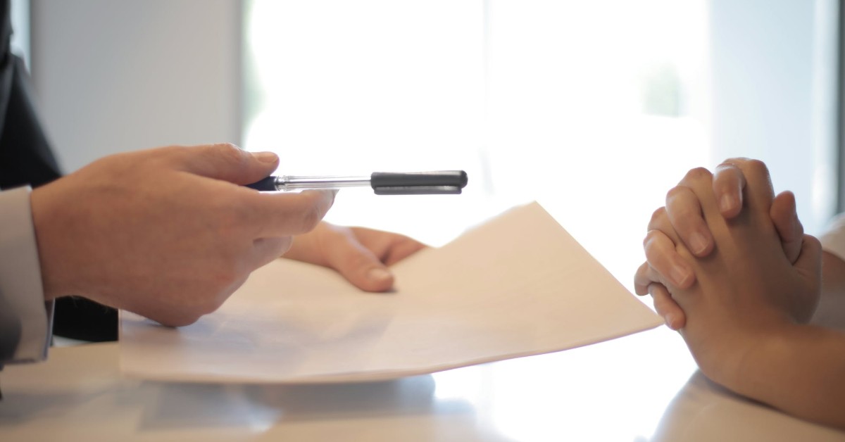 person handing paperwork to another person