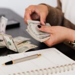 person holding cash writing in notebook