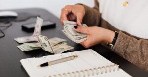 person holding cash writing in notebook
