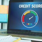 laptop opened to credit score sitting on desk with colorful pencils, notebooks and a plant