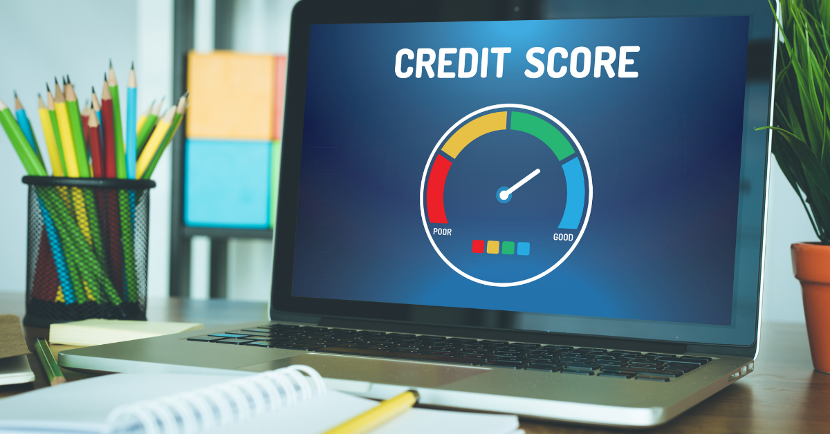 laptop opened to credit score sitting on desk with colorful pencils, notebooks and a plant