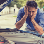 man looking under hood of his car that broke down