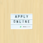 A white sign that says "APPLY ONLINE" in capital letters and has the MaxLend logo on the bottom corner of is on top of a beige-colored background. This indicates that the blog is about Applying for a Loan With MaxLend.