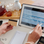 A person reviewing bills on a tablet while holding a credit card, with a notebook and calculator nearby, symbolizing financial planning and loan options for paying bills.