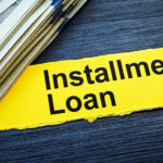 A stack of $100 bills sits on a table. The picture is labeled “Installment Loan.”