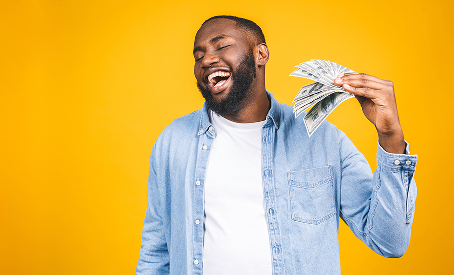 A smiling man waves a handful of cash. 